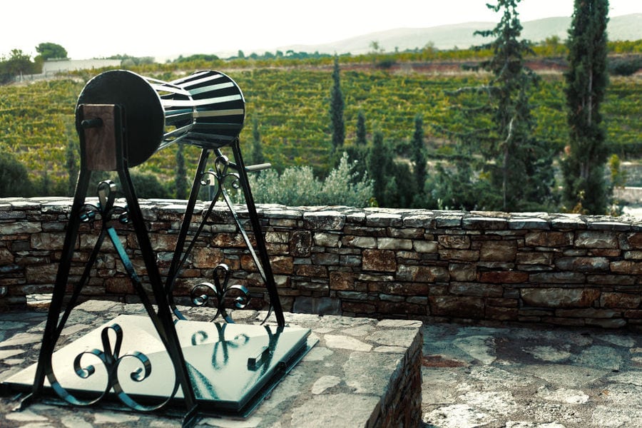 old well front the stone wall and Chateau Kaniaris winery vineyards